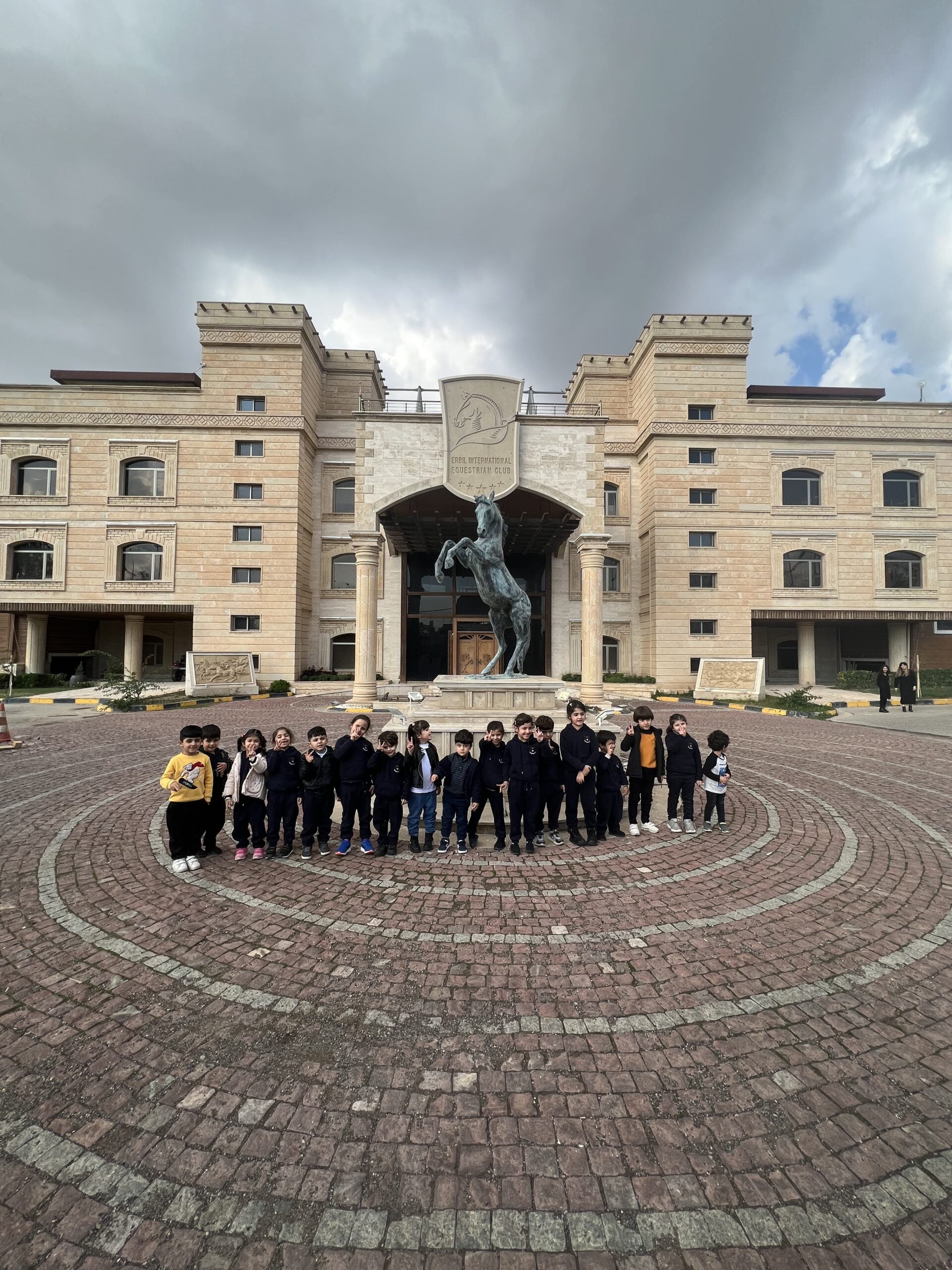 a group of sanny kindergarten erbil students standing in front of a statue